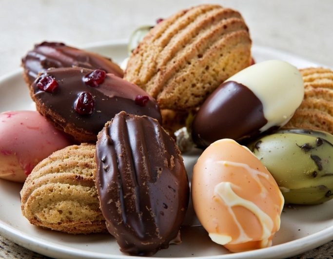 A plate of assorted pastries, including chocolate-covered and fruit-flavoured options.